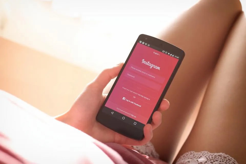 Mão segurando um celular com a tela de entrada do Instagram