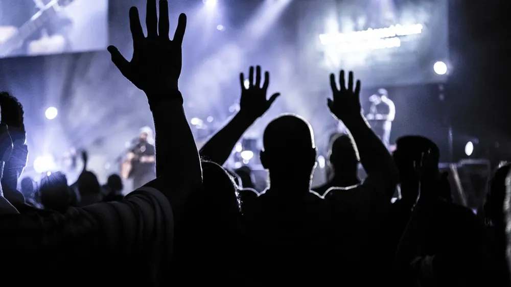 Pessoas com as mãos levantadas em adoração durante um culto