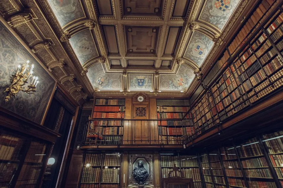 Biblioteca antiga com estantes de livros do chão ao teto e teto ornamentado